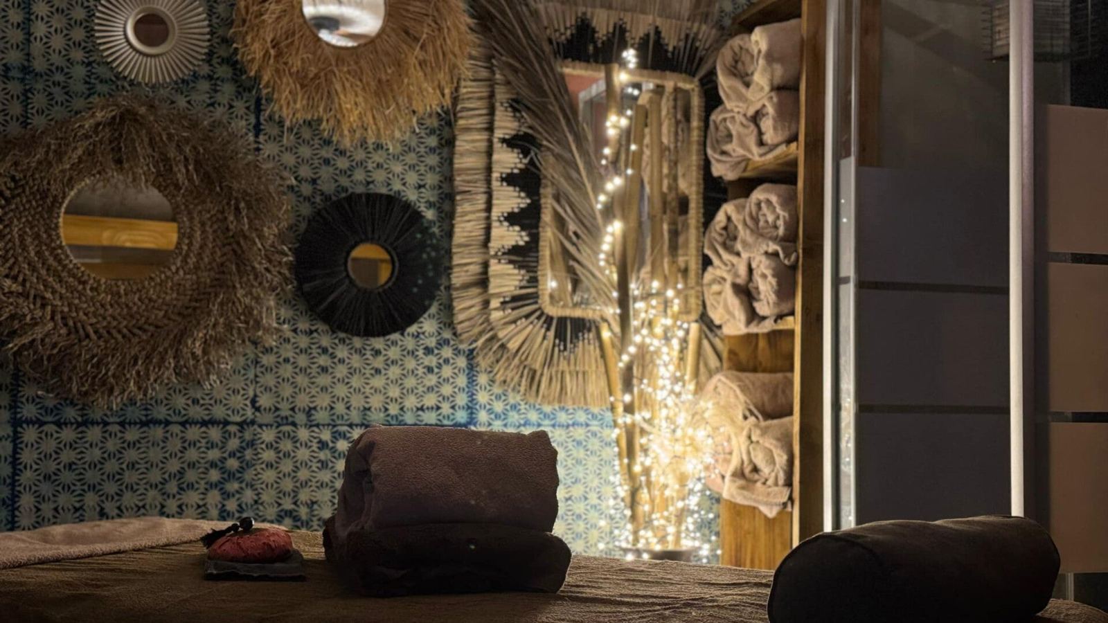 Mur de miroirs en fibres naturelles et guirlande lumineuse au-dessus de la table de massage